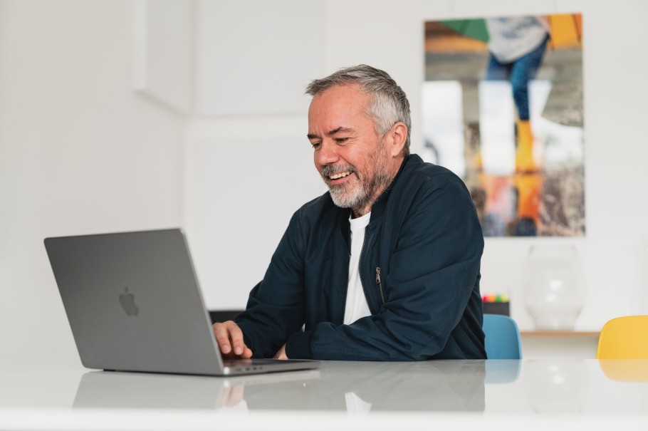 Ein etwa 40 jähriger Mitarbeiter sitzt an einem Tisch im Berliner Büro. Er schaut auf seinenn Laptop.