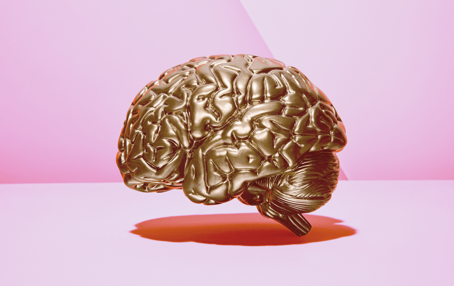 Ein goldenes Gehirn aus Metall schwebt in einem pinken Raum.