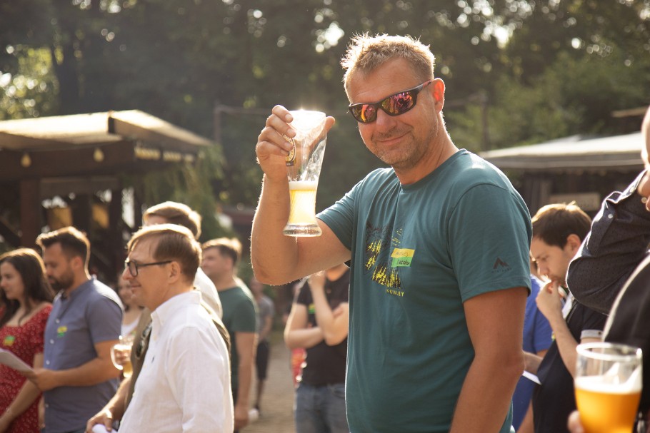 Mehrere Mitarbeiterinnen und Mitarbeiter auf dem Sommerfest in Dresden. Ein etwa 40 jähriger Mitarbeiter hebt das Glas.