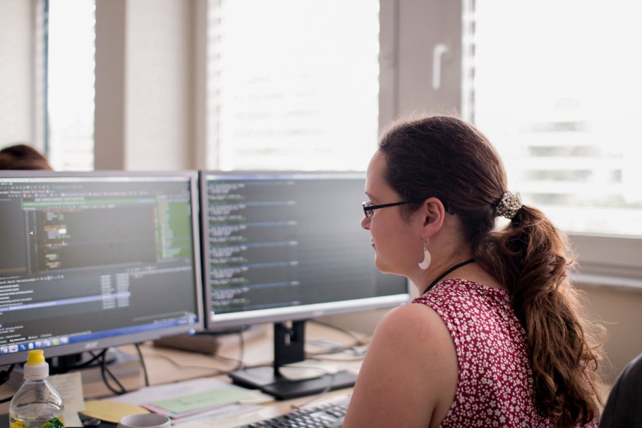 Unsere 30 jährige Mitarbeiterin Anke sitzt vor zwei Monitoren an ihrem Schreibtisch. Sie widmet sich dem Programmieren.